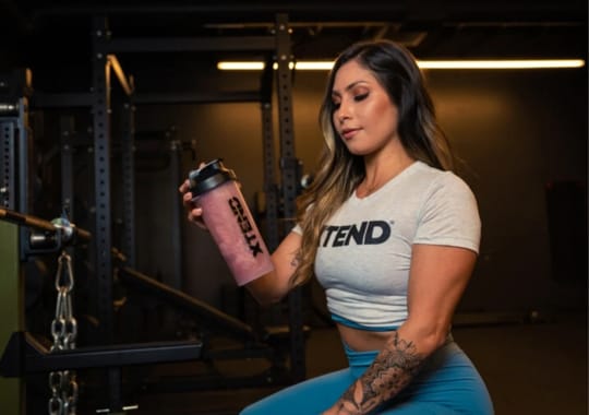 A woman holding a bottle of creatine and BCAA supplement.