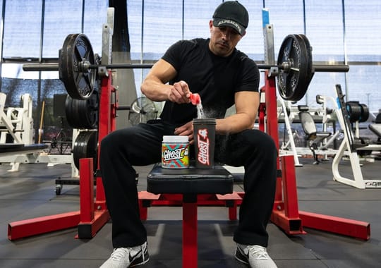 A man mixing ghost pre-workout supplement in a bottle.