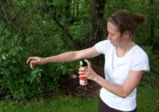 A lady holding a bottle of bug spray.