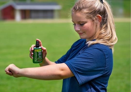 A lady holding a bottle of bug spray.