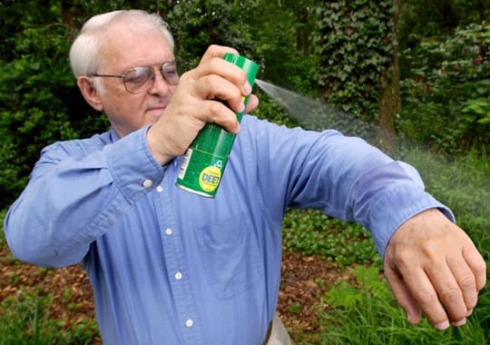 A man spraying himself bug spray.