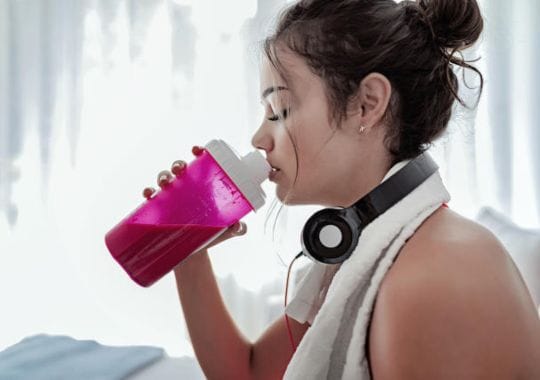 A woman drinking pre workouts supplement.