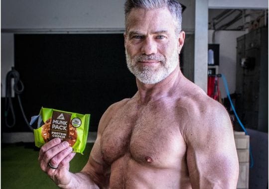 A man holding a pack of protein cookies.