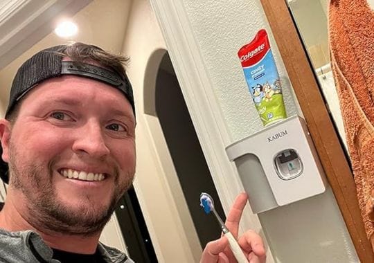 A man holding a toothpaste dispenser.