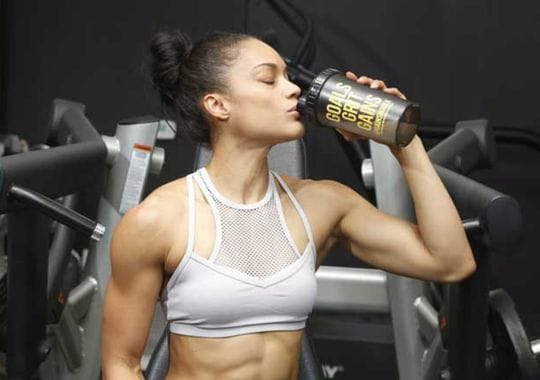 A woman drinking pre workout supplements.