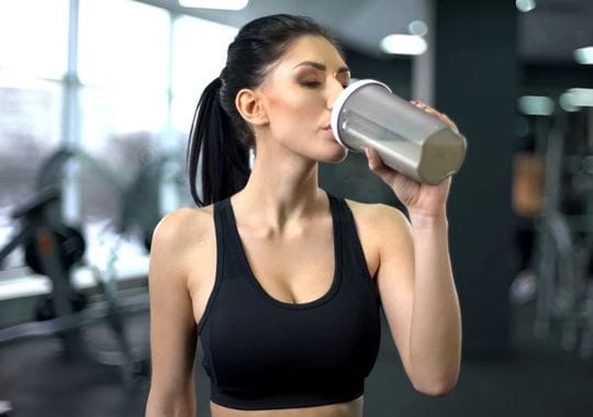 A woman drinking pre workout supplement.