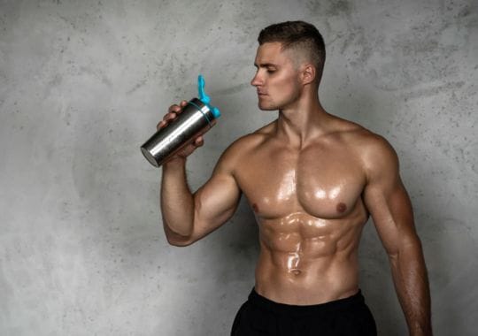 A man holding a bottle of pre workouts.