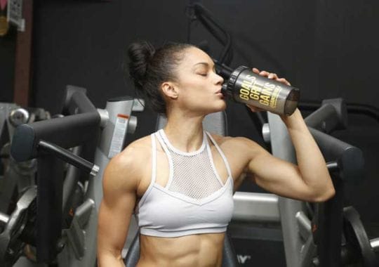 A woman drinking pre workout supplements.