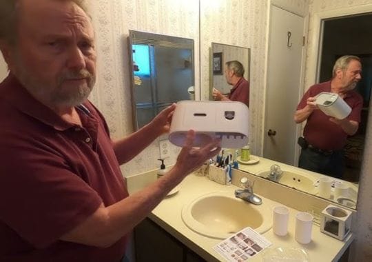 A man holding a toothpaste dispenser.