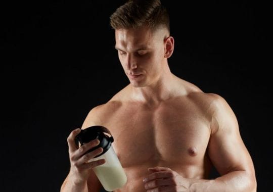 A man holding a bottle of pre workouts.