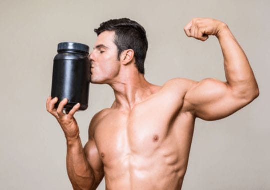 A man holding a bottle of pre workouts.