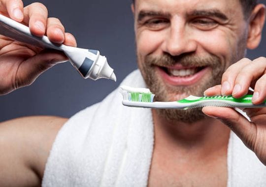 A man putting toothpaste on a tooth brush.