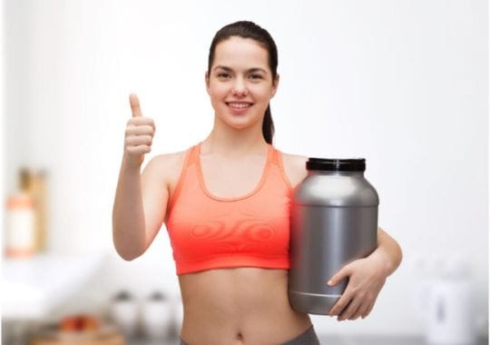 A woman holding a bottle of Protein powder.