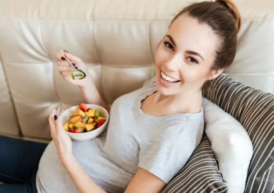 A pregnant woman eating fruits.