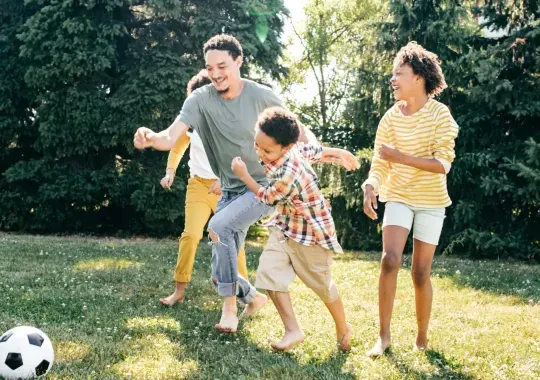 A man playing soccer with his family.