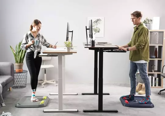 Two people using fezibo standing desks to work.