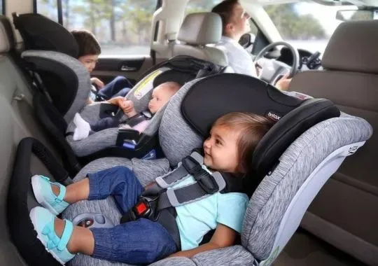 Two babies put in car seats.