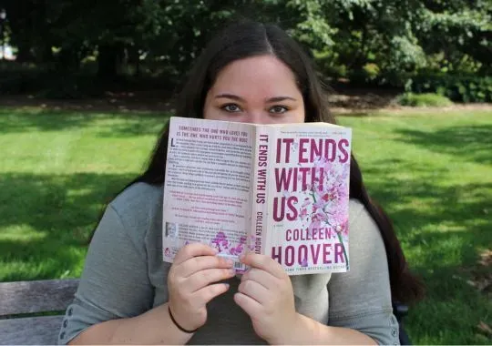 A woman holding the best colleen hoover book.