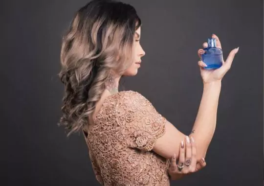 A woman holding a bottle of perfume.