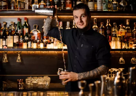 A bartender making a drink in a bar.