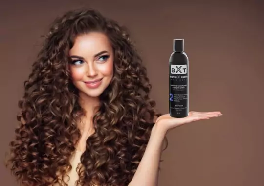 A woman holding a bottle of hair shampoo.